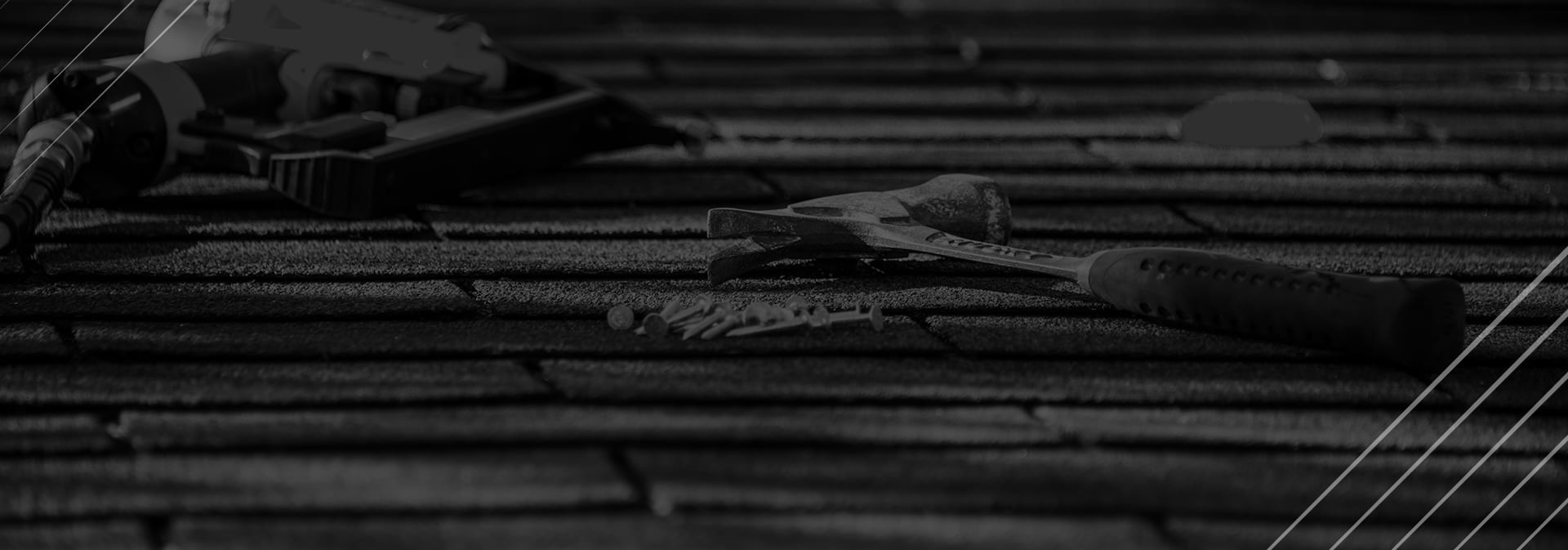 Roofing tools including a hammer and nails on a shingled roof