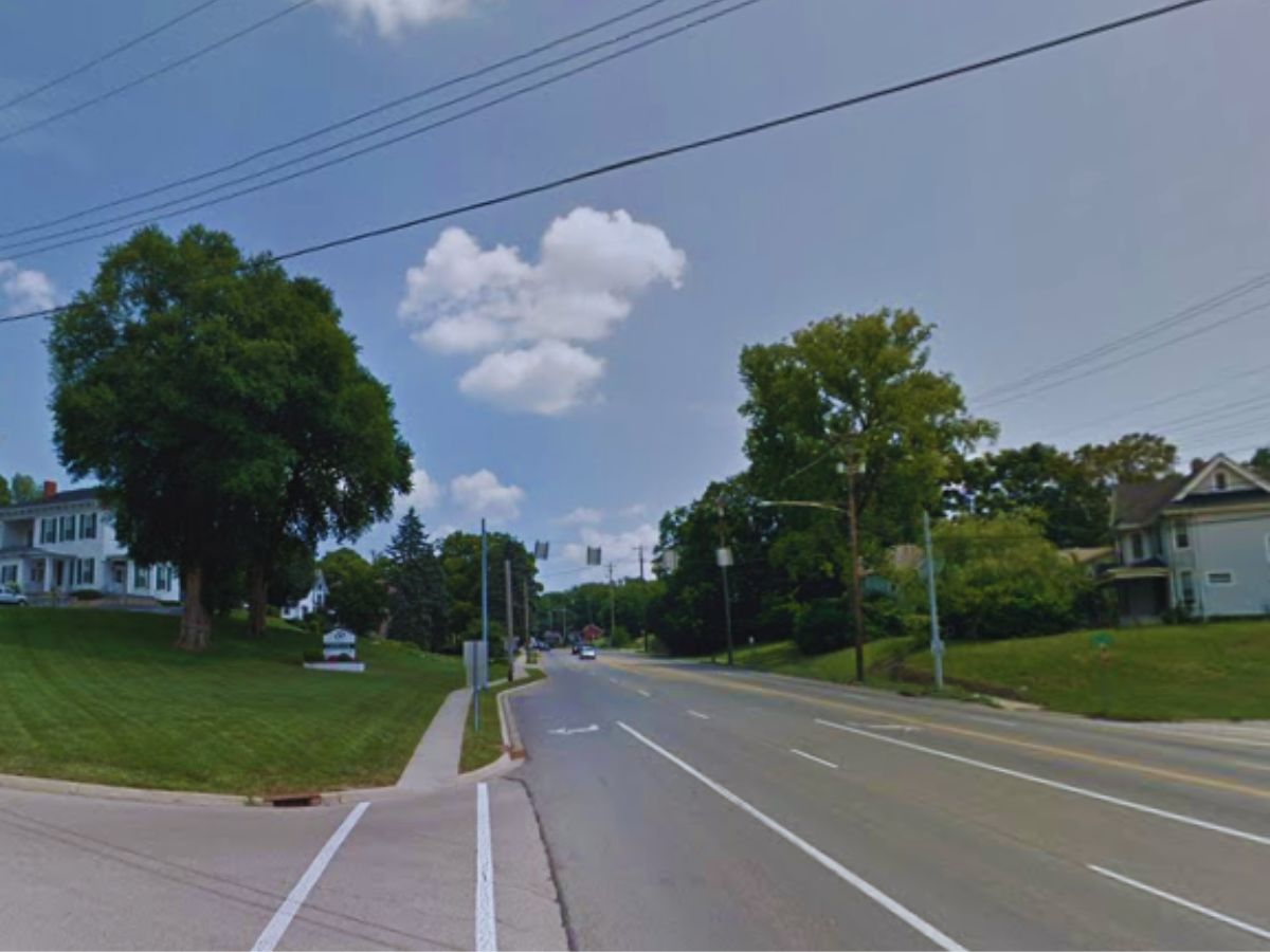 The suburb intersection at 115 High St in Franklin features houses, trees, and a traffic light. Power lines cross above on a clear OH day.