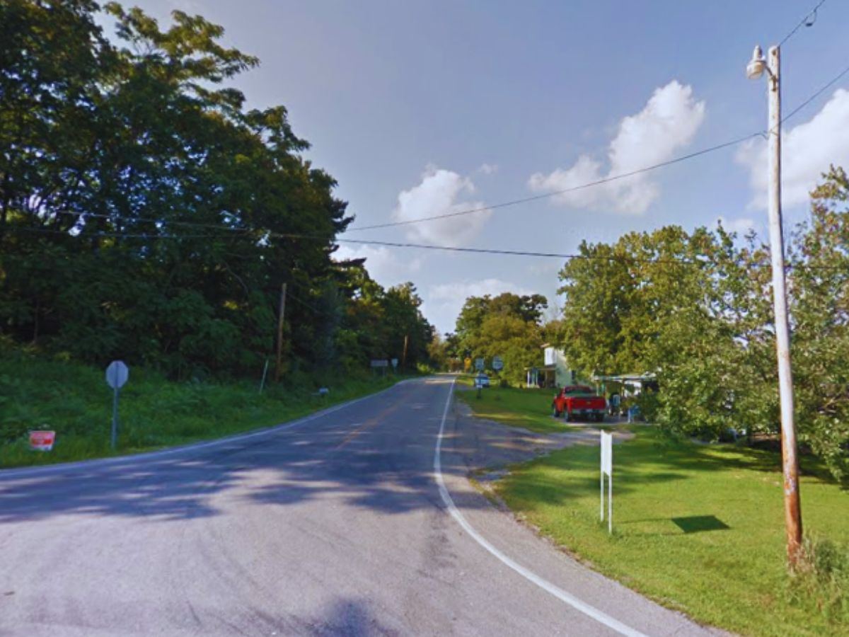 Curving rural road in West Chester, OH, with trees on the left and red vehicles parked along 6300 OH-342 Rd. Utility pole and signposts nearby.