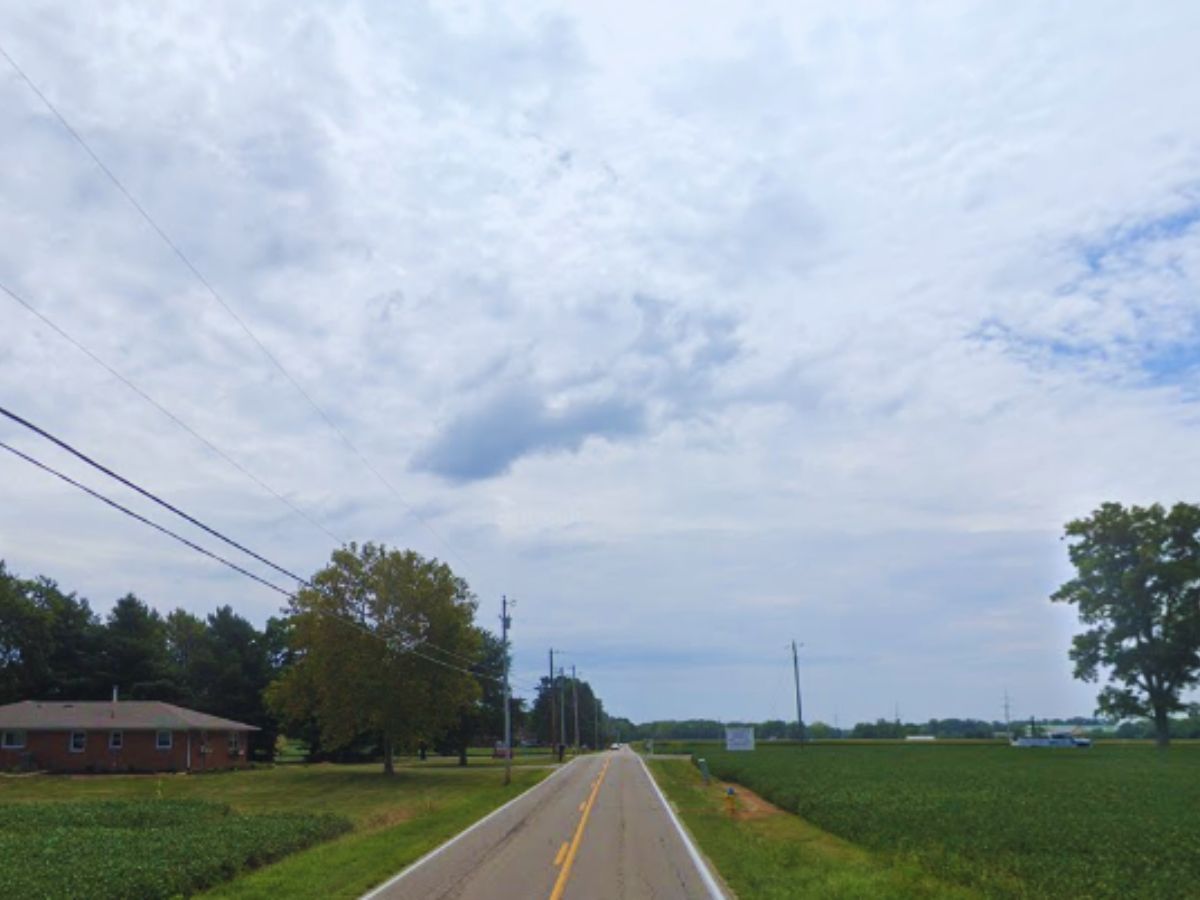 A rural road stretches into the distance on 9520 Haber Rd, flanked by fields, power lines, and trees under a cloudy Clayton sky.