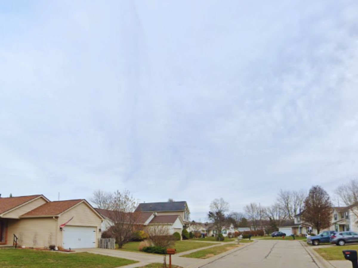 Quiet suburban street in Maineville with single-story houses, driveways, and parked cars under a cloudy sky at 98 Willow Ridge Ct.