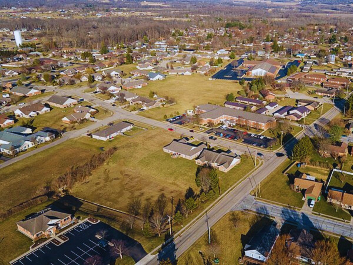 Aerial view of Bellbrook, OH's suburban neighborhood with houses, roads, and lush green spaces nestled among trees and fields.