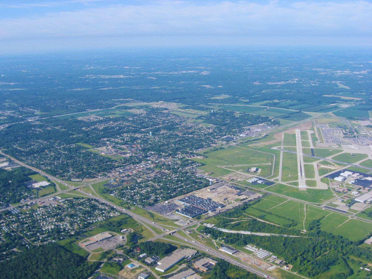 Aerial view of Vandalia, OH, showcasing a prominent airport runway amidst urban and green areas under a clear blue sky.