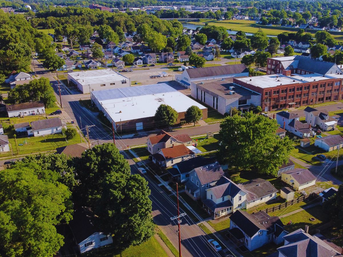 Bird view of a suburban neighborhood in Piqua, OH, showcasing residential houses and tree-lined streets on a sunny day.