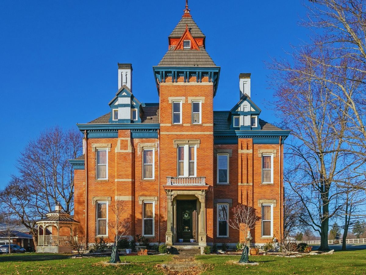 A large, red-brick Victorian-style house in Germantown, known as the David Rohrer House, boasts multiple chimneys and a central tower under a clear blue sky.