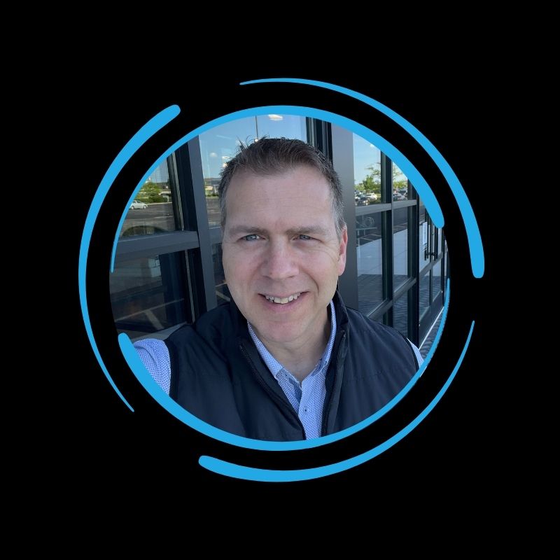 Smiling man standing outside near an All-Side roofing building, framed by a blue circular graphic on a black background.