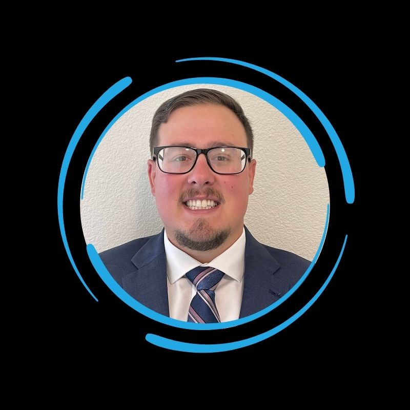 A man in a suit and tie with glasses smiles at the camera, framed by blue circular graphics, in this All-Side roofing about image.