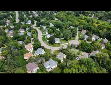 Aerial view of a Greene County, Ohio suburban neighborhood with houses, curved streets, and abundant green trees.