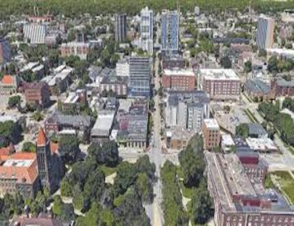 Aerial view of Champaign County, OH cityscape with mid-rise buildings, roads, and green trees scattered throughout the area.