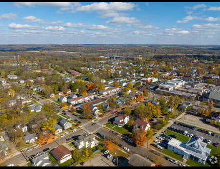 Aerial view of a Butler County OH suburban neighborhood with houses, streets, trees, and commercial buildings under a partly cloudy sky.