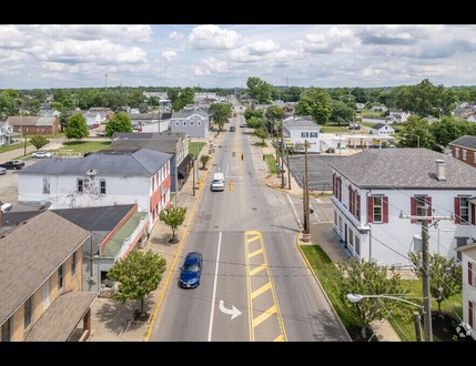 Aerial view of an Ohio small town street in Butler County, with cars, buildings, trees, and a cloudy sky above.