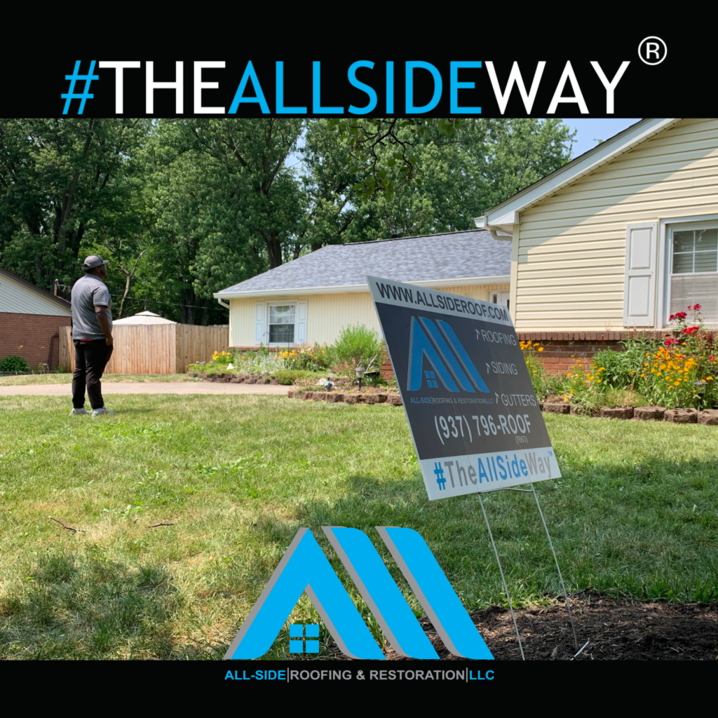 A sign for All-Side Roofing & Restoration advertises roof replacement in Trenton, OH, with a person standing on the lawn beside the house.