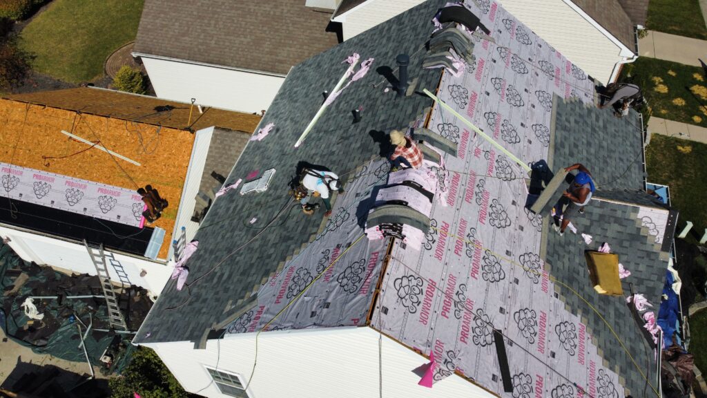 Aerial view of workers installing shingles and underlayment during a roof replacement project in Lebanon OH.