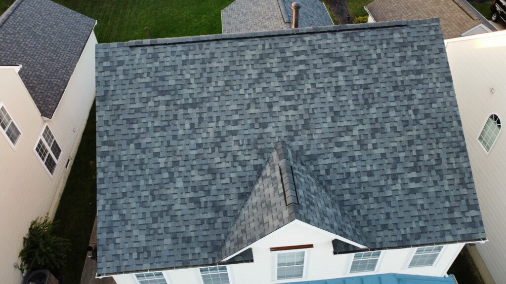Aerial view of a gray shingled roof on a white house in Lebanon OH, highlighting recent roof replacement and green lawns.