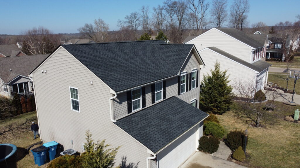 Two-story beige house in Morrow OH with black shingle roof, white trim, garage, driveway; ideal candidate for roof replacement.