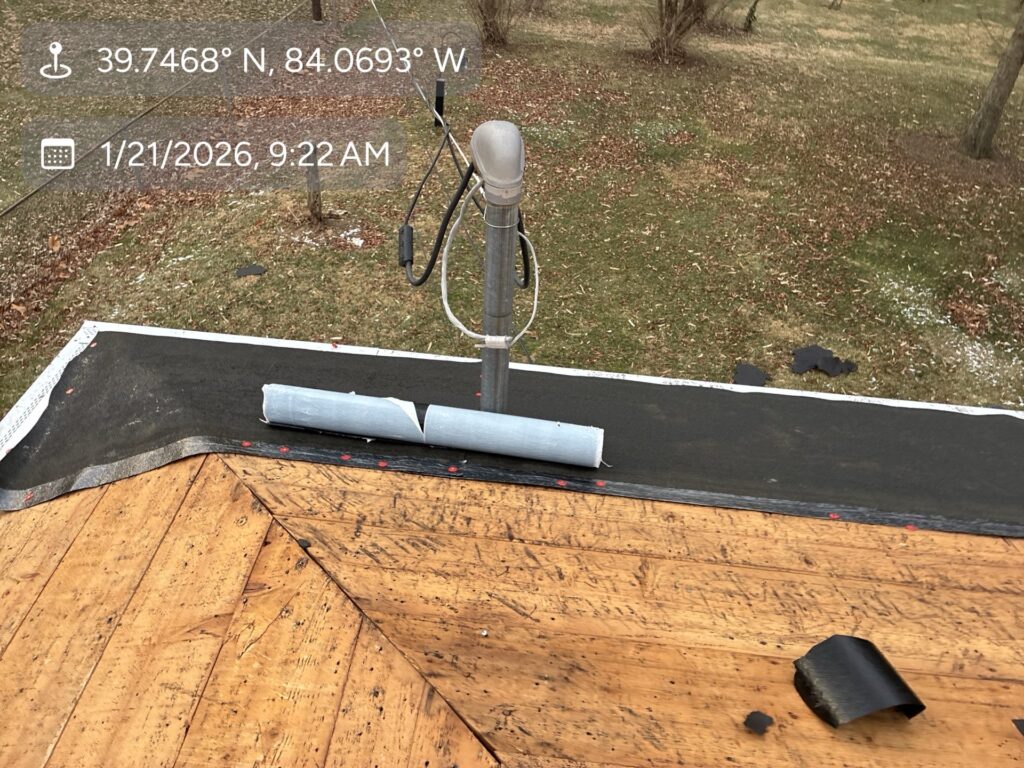 Wood decking, a black underlayment strip, and a plumbing vent pipe during a Beavercreek roof replacement.